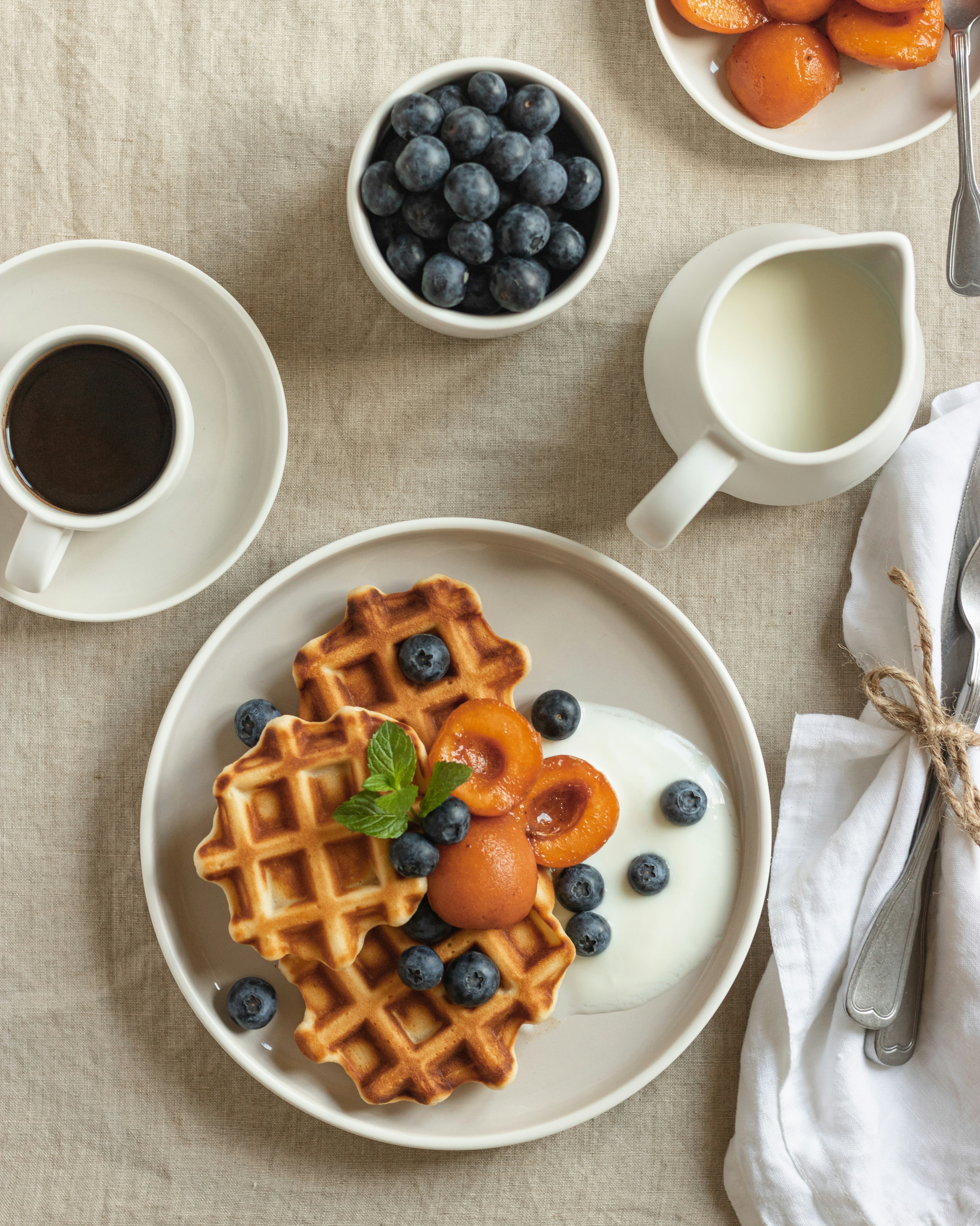 waffle with sliced strawberries and blueberries on white ceramic plate